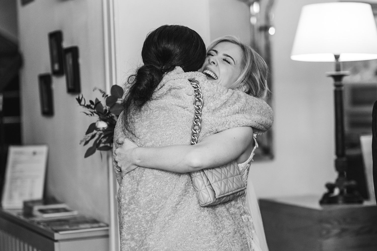 Joyful black and white moment capturing emotional embrace at wedding celebration.