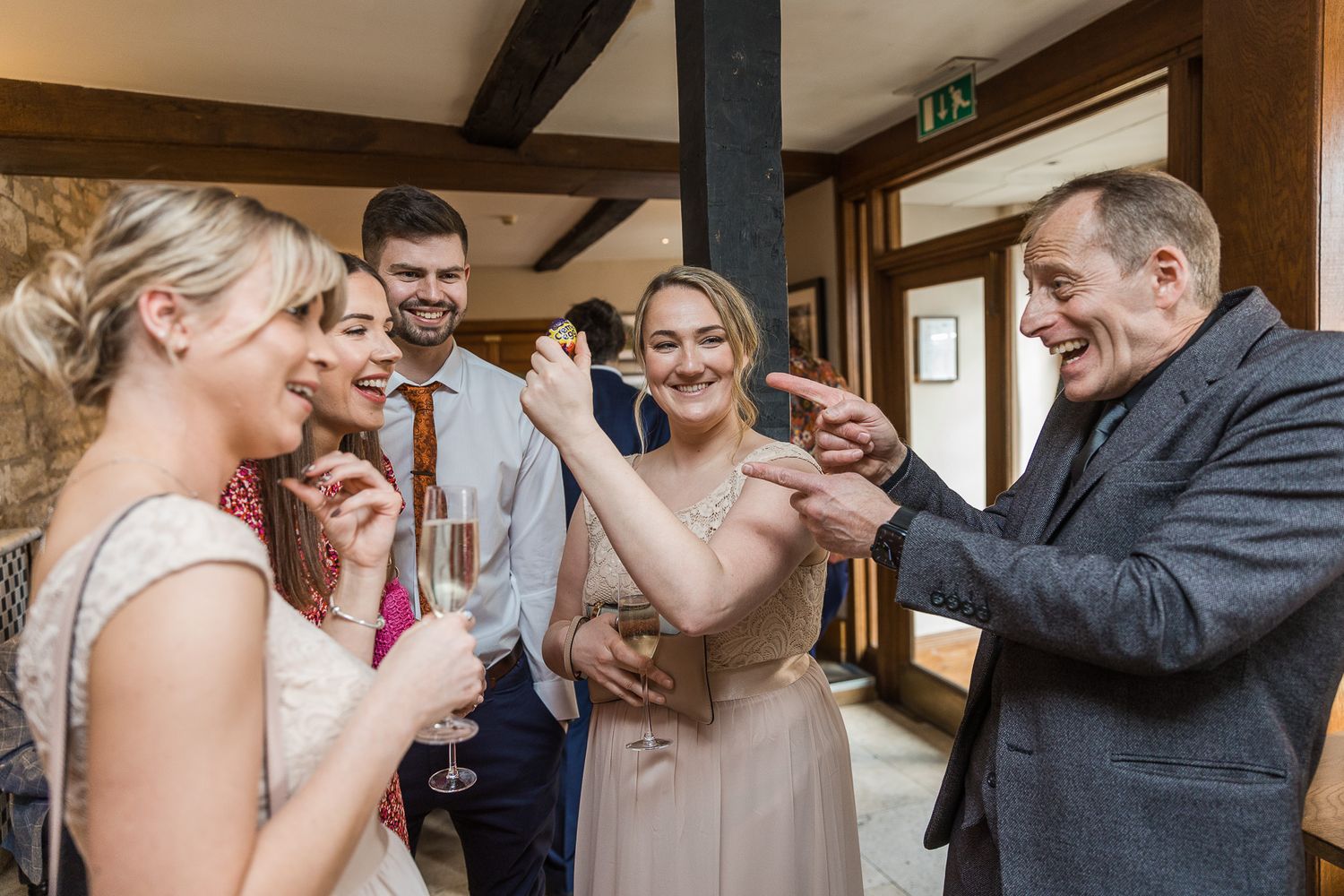 Wedding guests share a joyful moment while drinking champagne together at an indoor reception.