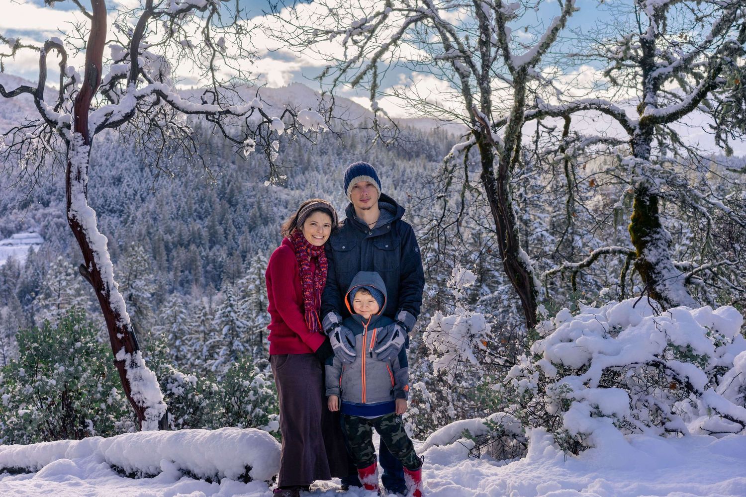 family of 3 surrounded by snow and mountains