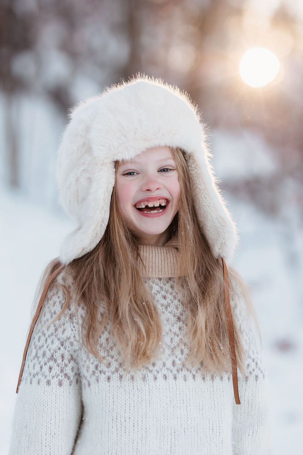 Jente som smiler i snøen med lue på