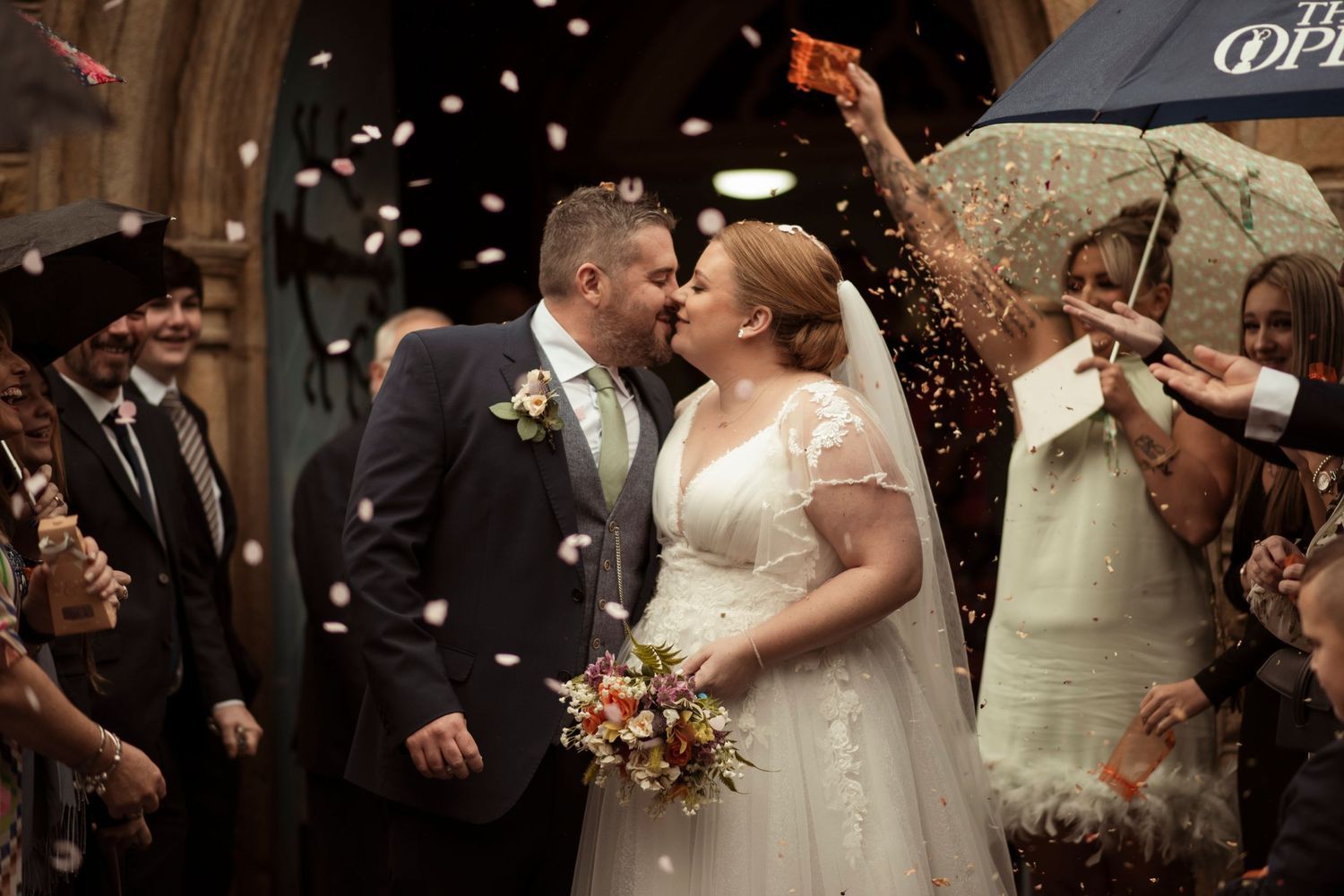 Bride and groom kissing surrounded by confetti