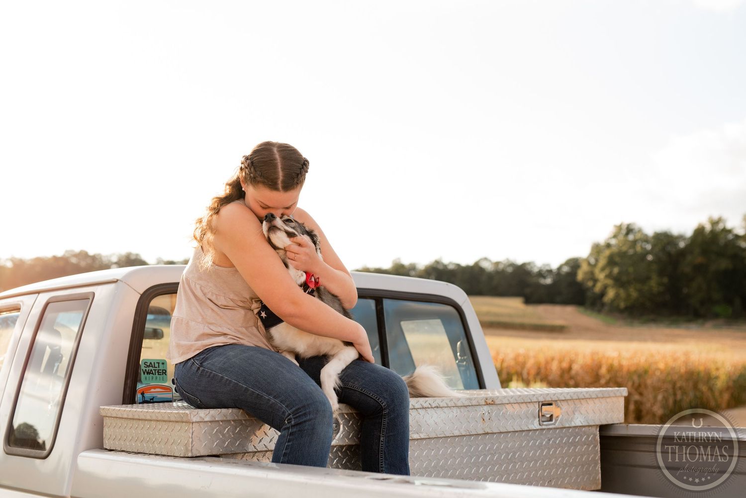A heartwarming moment captured on a pickup truck bed with corn fields in the distance.