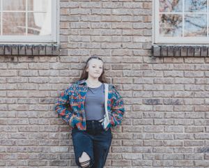 Fashion portraits against a textured brick wall with natural lighting.