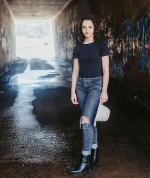 Moody tunnel photoshoot with dramatic lighting and reflective puddles on ground.