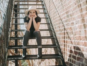 Playful portrait series on industrial metal stairs with brick background.