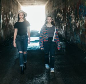 A moody photoshoot in a graffiti-covered tunnel with dramatic lighting and shadows.