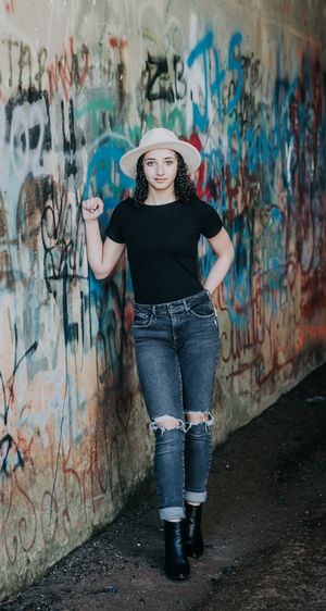 Artistic photo series in graffiti tunnel showing figure in black shirt and ripped jeans against colorful wall.