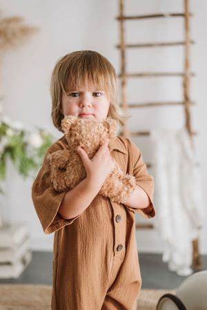 A heartwarming moment with a teddy bear and brown button-up outfit in a bright room.