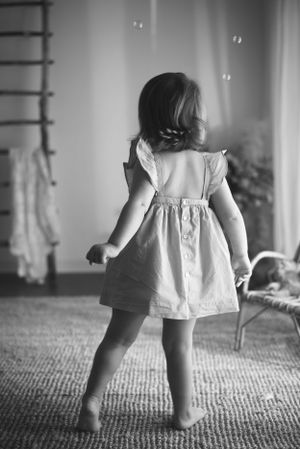 Black and white image showing a twirling white dress against a textured carpet.