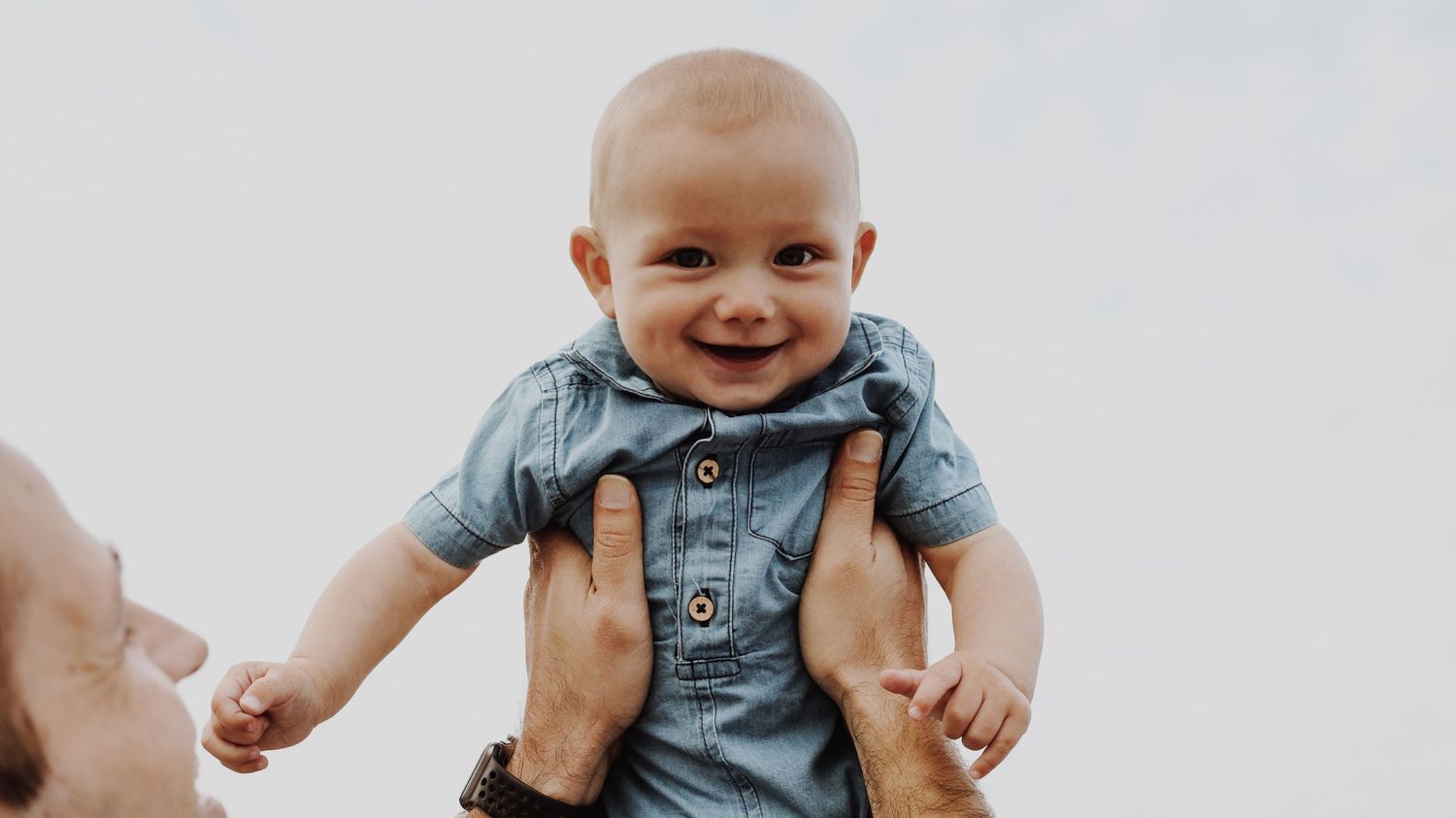 A portrait of a person smiling, captured in natural light, with a simple background.