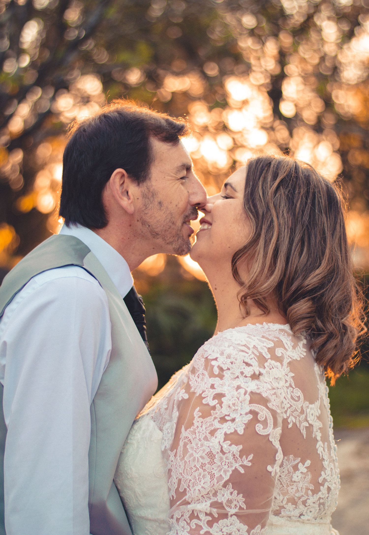 Intimate wedding portrait of couple sharing tender moment at sunset.