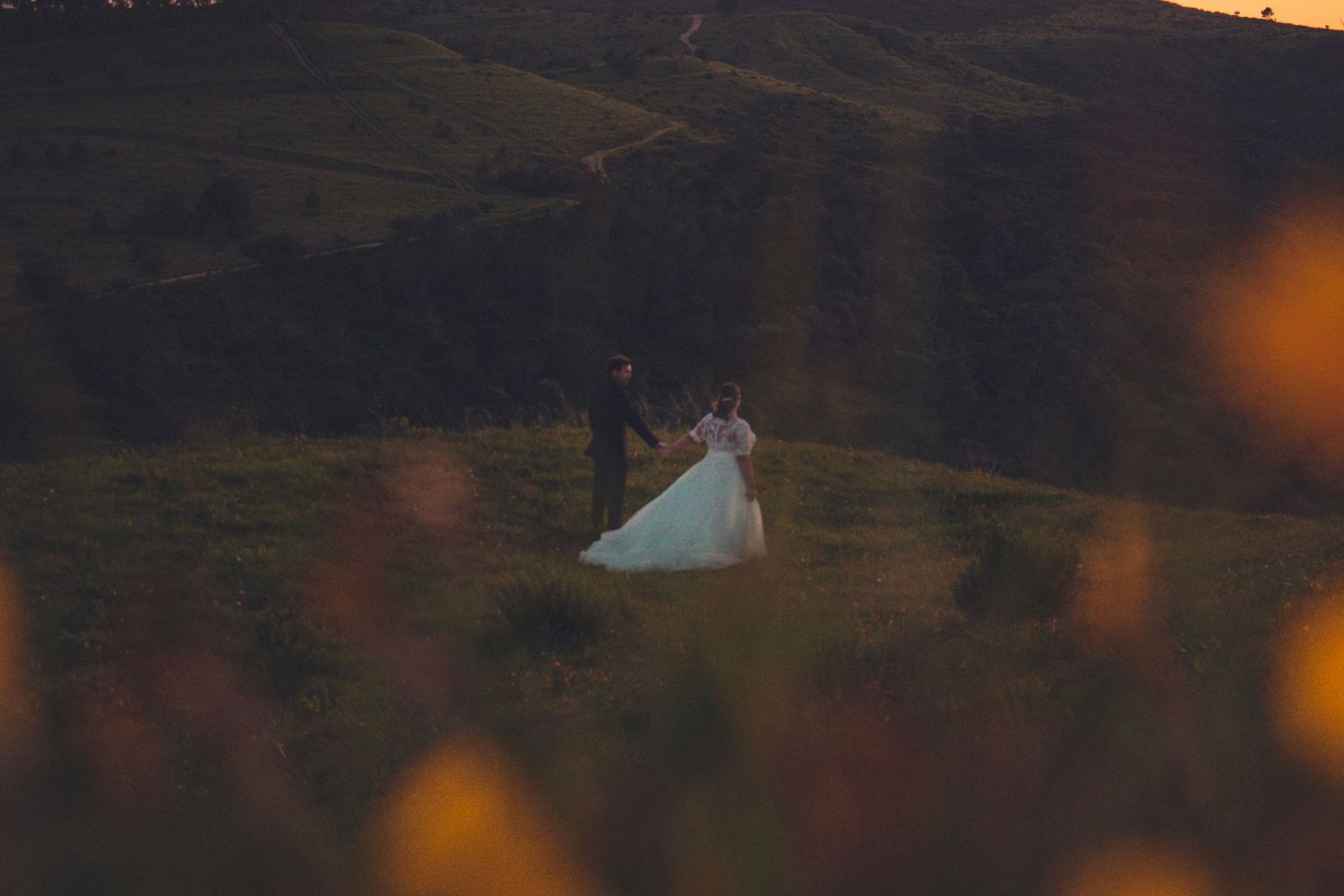 Dramatic sunset sky with deep orange and purple hues casting silhouettes against a mountainous landscape.