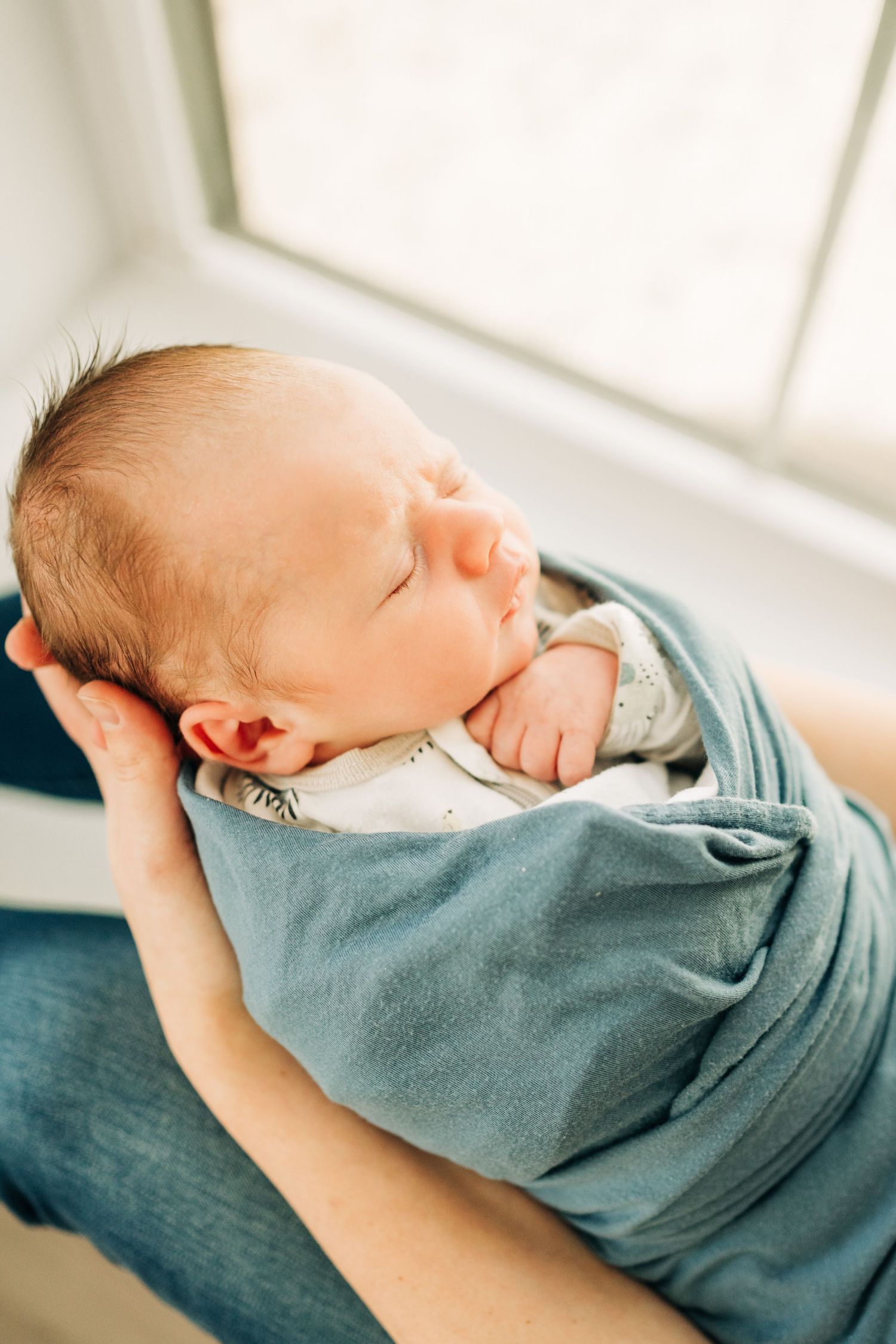 Mom cuddling newborn baby during lifestyle newborn session in Dallas, TX