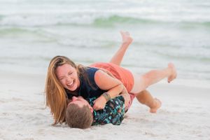 fun couple rolling in the sand on Panama City Beach Florida