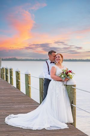 beautiful couple embracing each other on the dock on their wedding day at sunset on Panama City Beach Florida