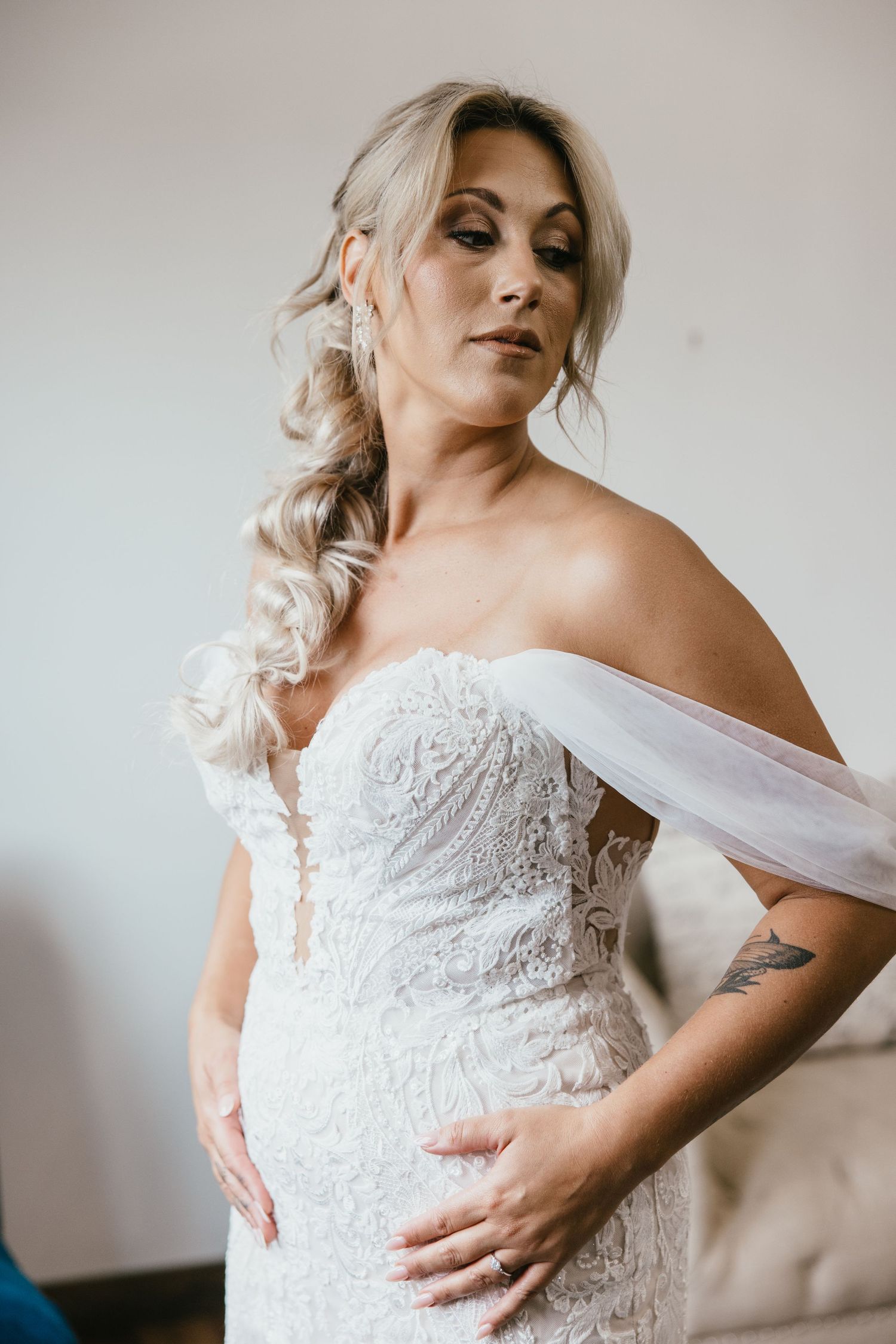 Close-up of bride in lace off-shoulder wedding dress with elegant hairstyle.