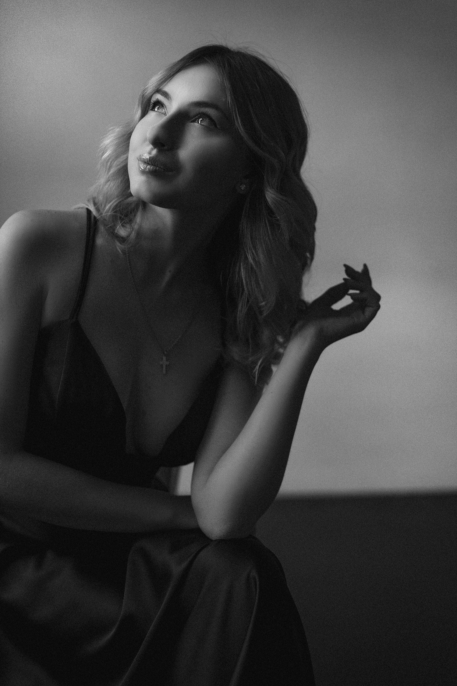 Dramatic black and white portrait of a woman in elegant dress looking upward with artistic lighting.