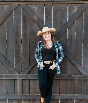 Country western style portrait with cowboy hat and plaid shirt against rustic wooden barn door.