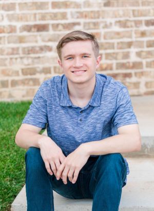 Casual portrait against brick wall wearing blue heathered polo shirt.