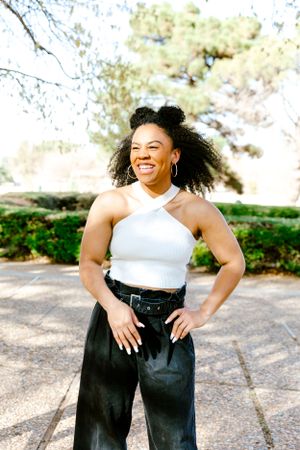 Person in white halter top and black pants poses confidently outdoors.