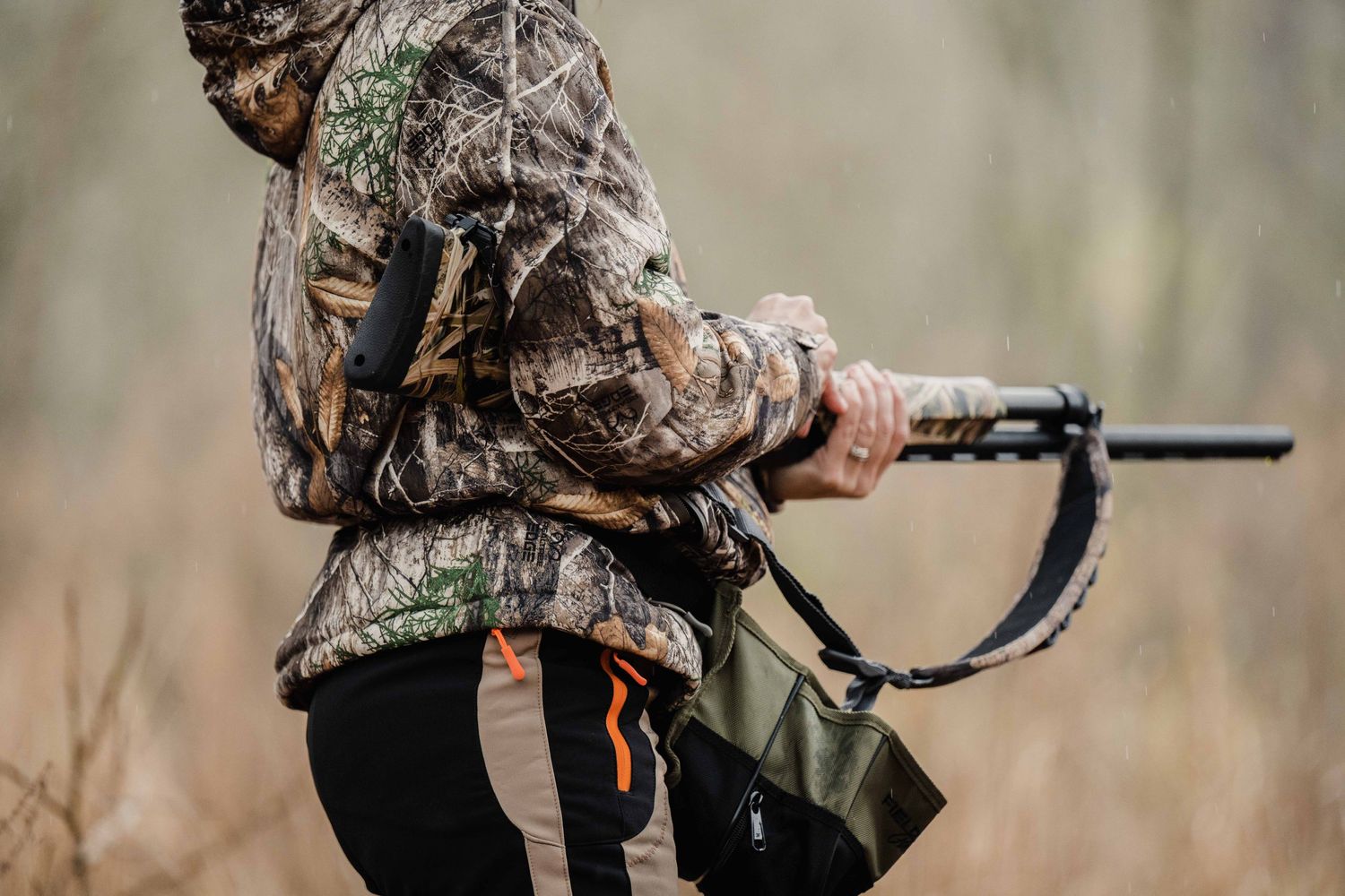 Hunters carrying rifles through wooded terrain during hunting season.