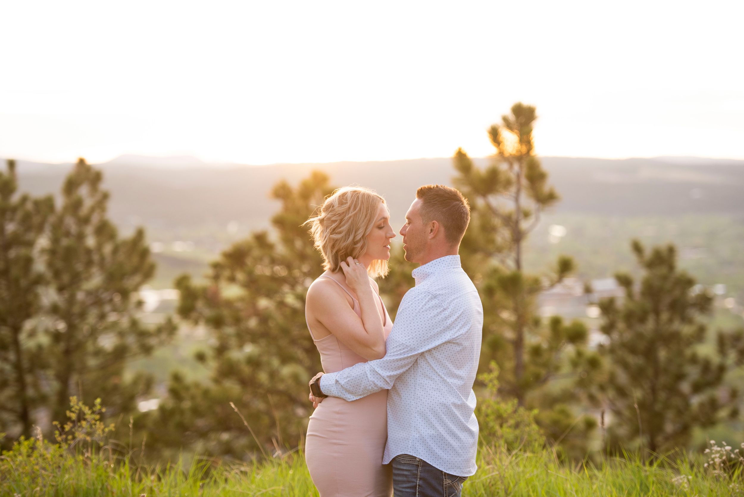 Intimate engagement session at sunset with soft lighting and mountain views.