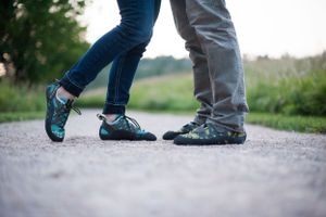 Close-up of two pairs of feet walking together on a gravel path.