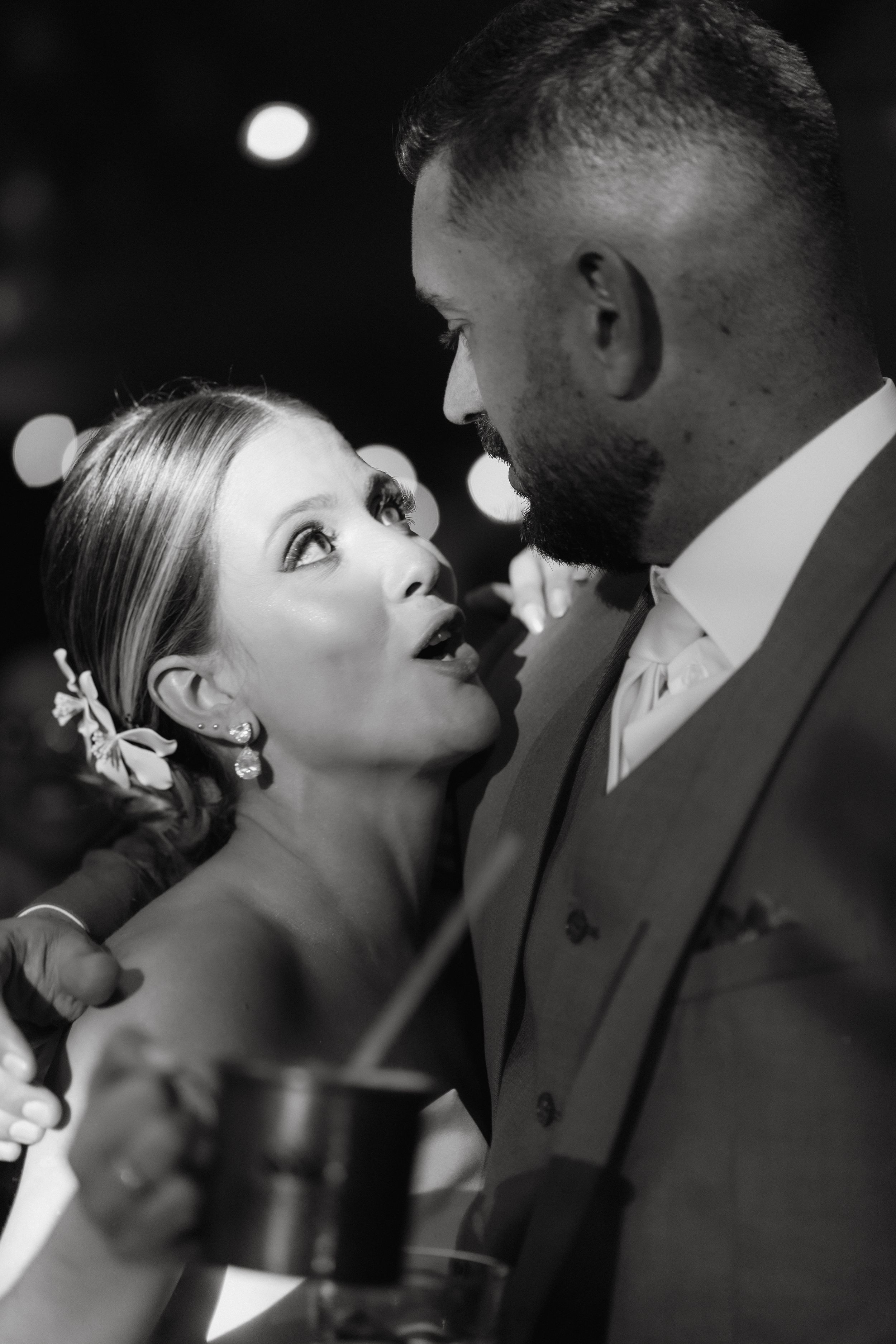 A black and white romantic moment between newlyweds sharing an intimate glance at their wedding reception.