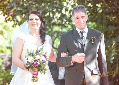 Outdoor wedding ceremony under trees with bridal party in formal attire.