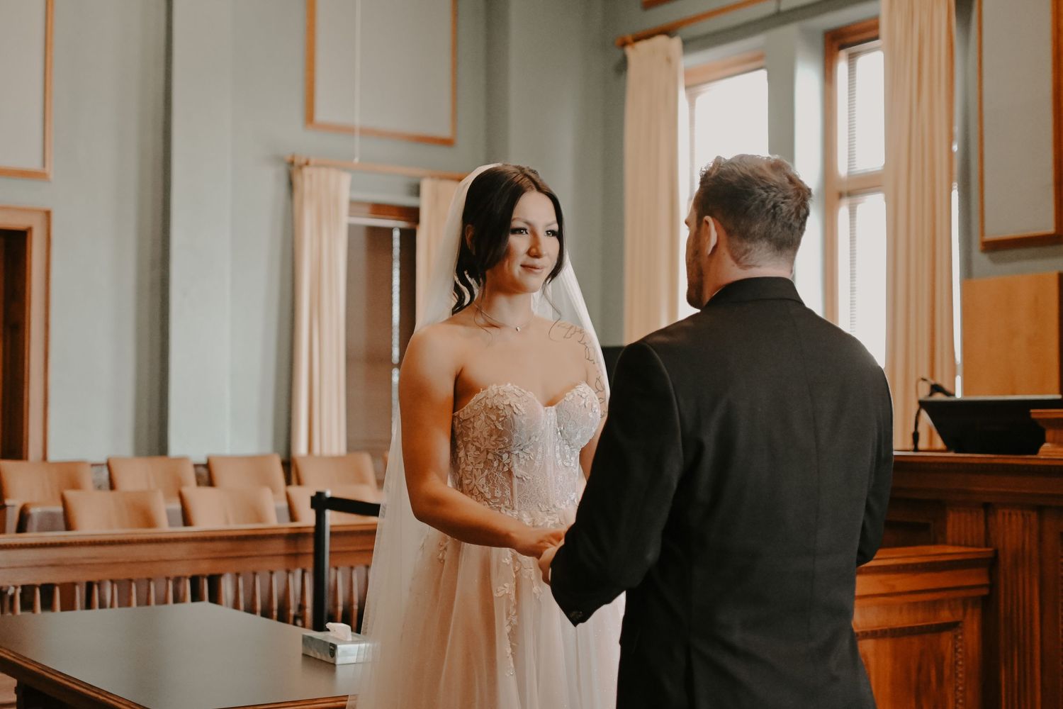 Elegant wedding ceremony taking place in a traditional courtroom with wooden furnishings.
