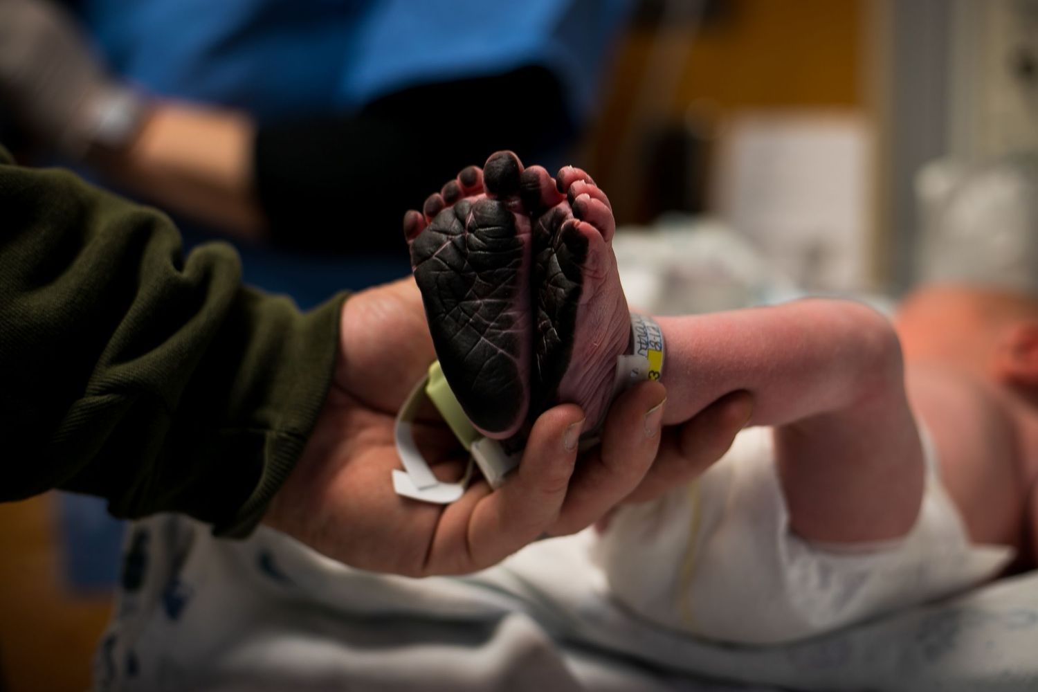 Dad holding his newborn son's feet just after the nurse had put ink on them for newborn footprints in Sioux City, IA.