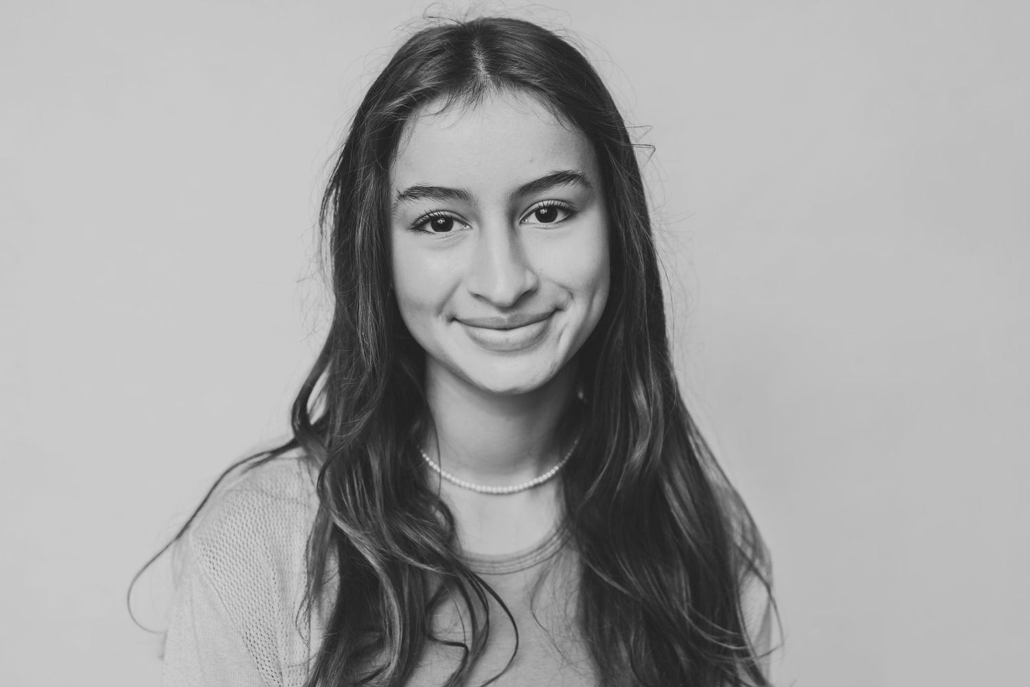 Black and white portrait of a person smiling warmly at the camera.