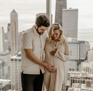 Intimate maternity moment shared against urban skyline backdrop.