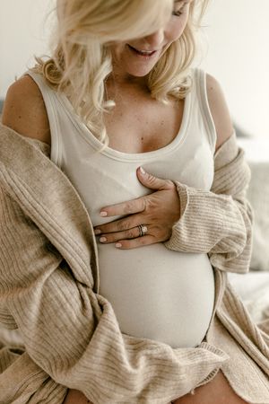 Close-up maternity portrait showing gentle hands on belly in soft natural light.