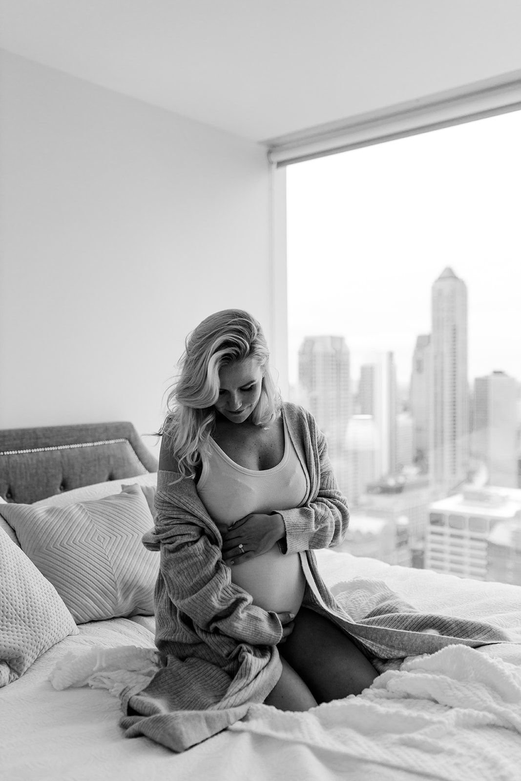 Peaceful black and white maternity portrait with city backdrop.