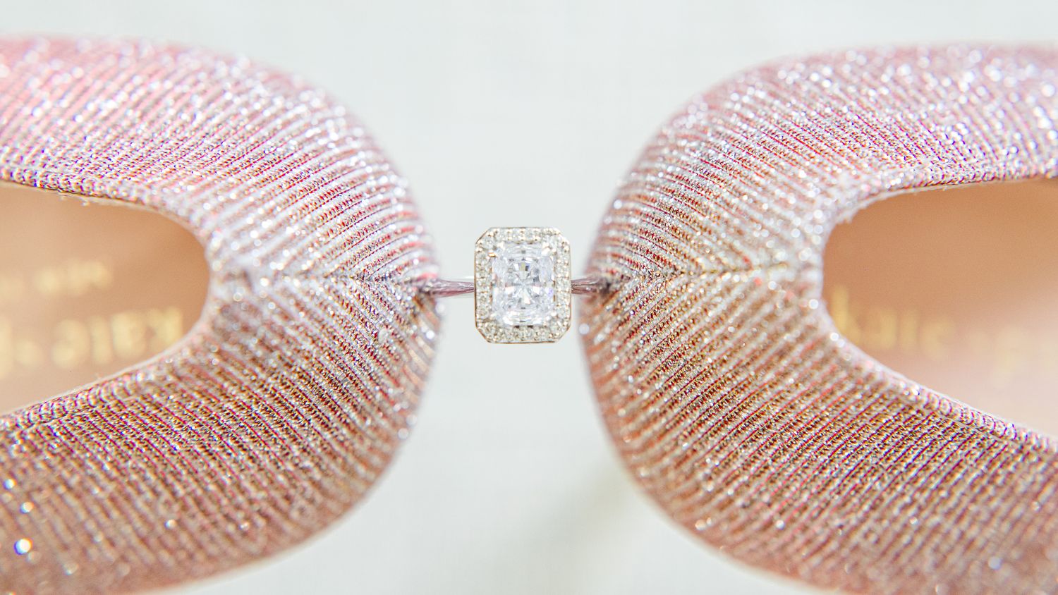 Sparkling diamond engagement ring held delicately between two glitter-covered pink heels by Stephanie Coulter Photography