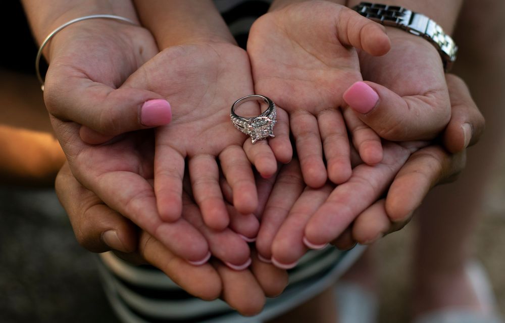 mom, dad, and daughter show engagement ring