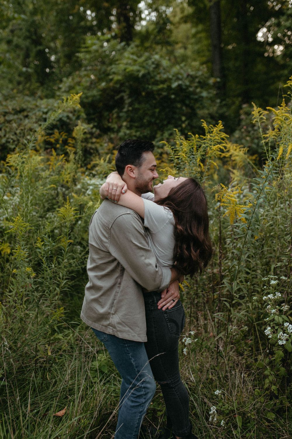 A romantic couple sharing a tender moment in a field of goldenrod on a misty day.