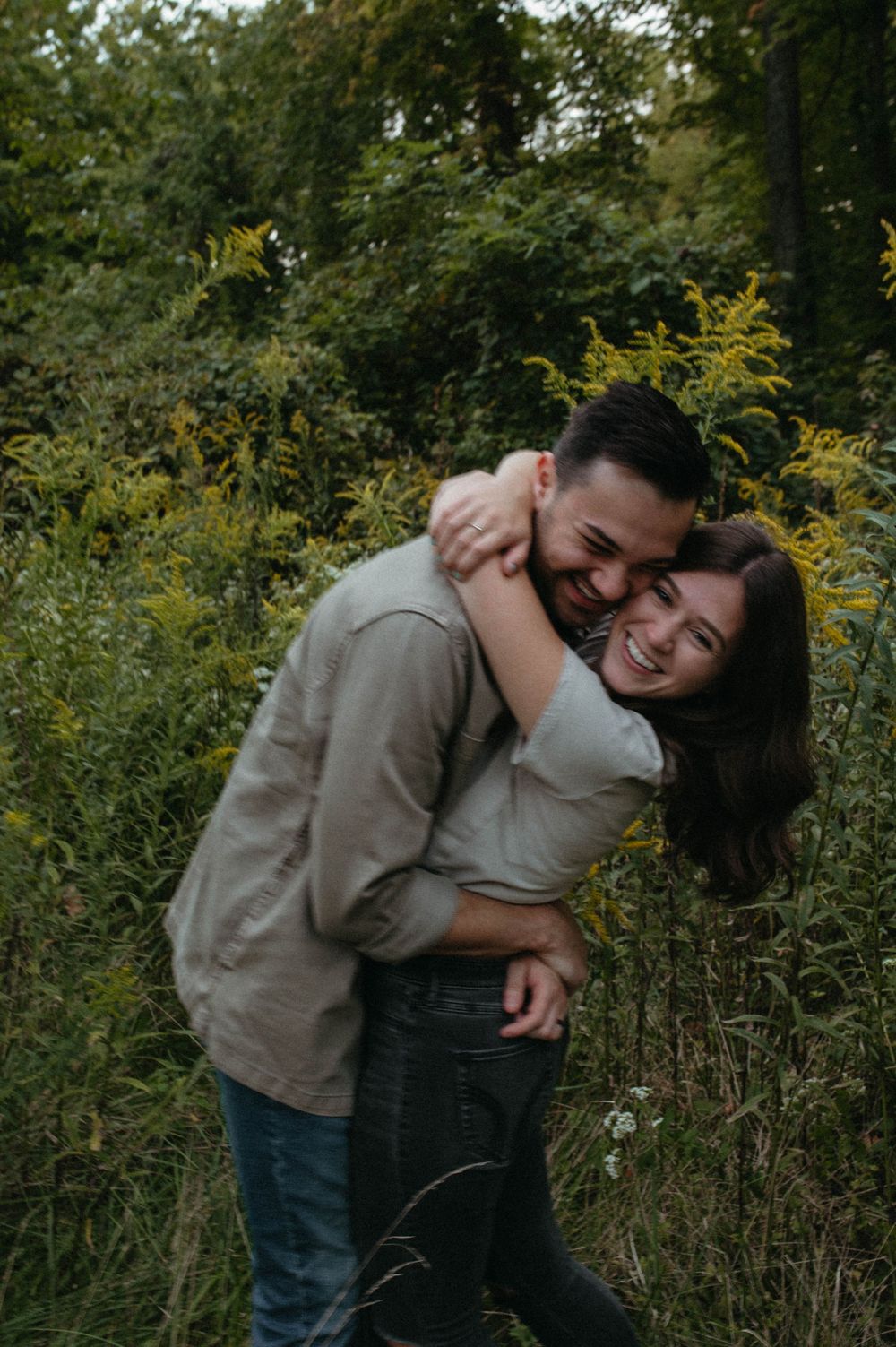 A candid moment of laughter and joy between a couple in a wildflower meadow.