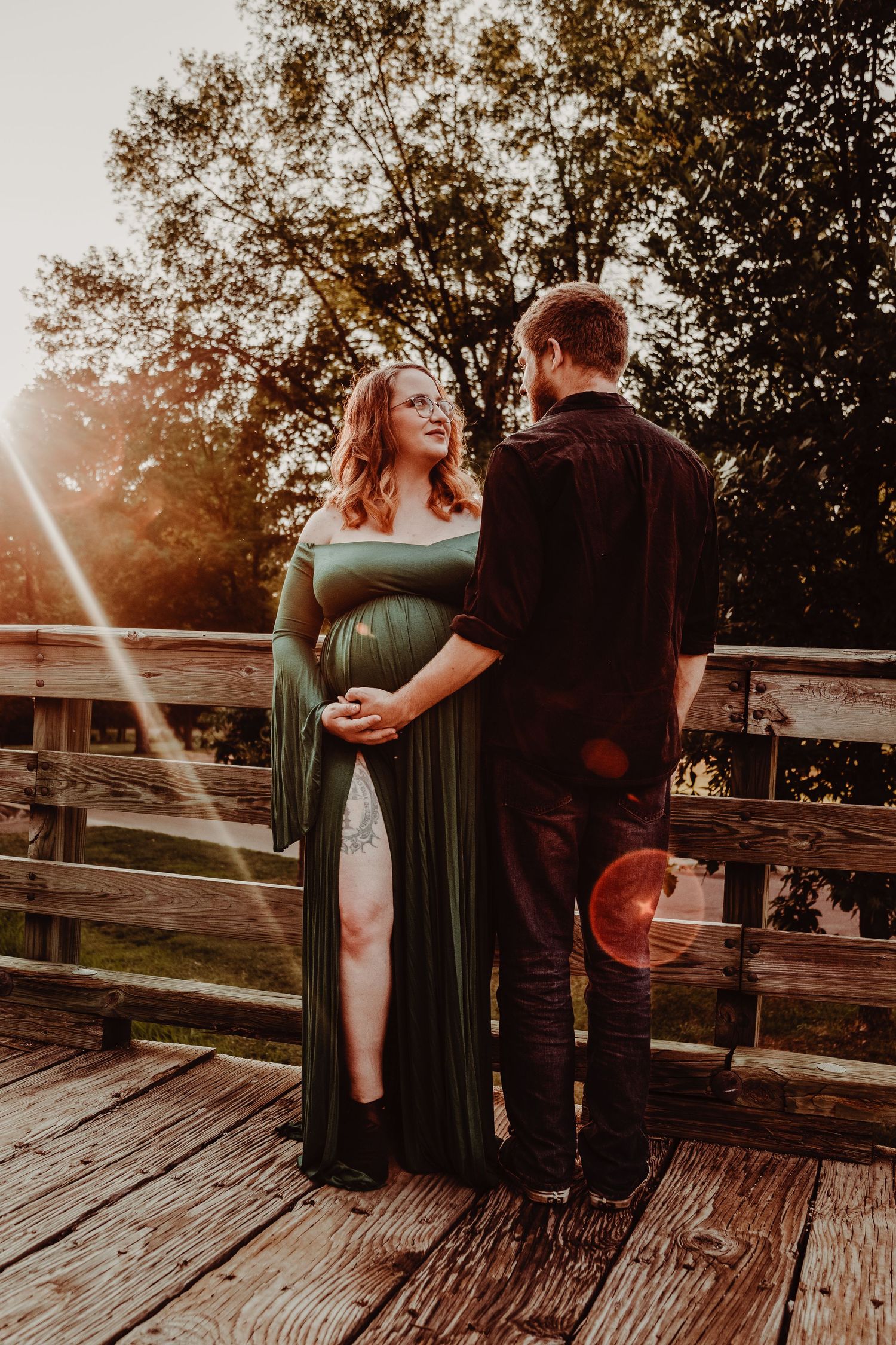 Intimate sunset portrait on a rustic wooden bridge deck with warm backlighting.