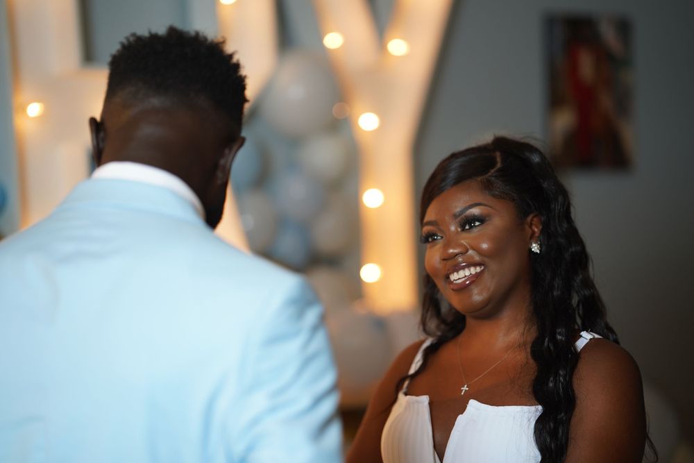 An intimate wedding moment captured with decorative lights and balloons in the background.