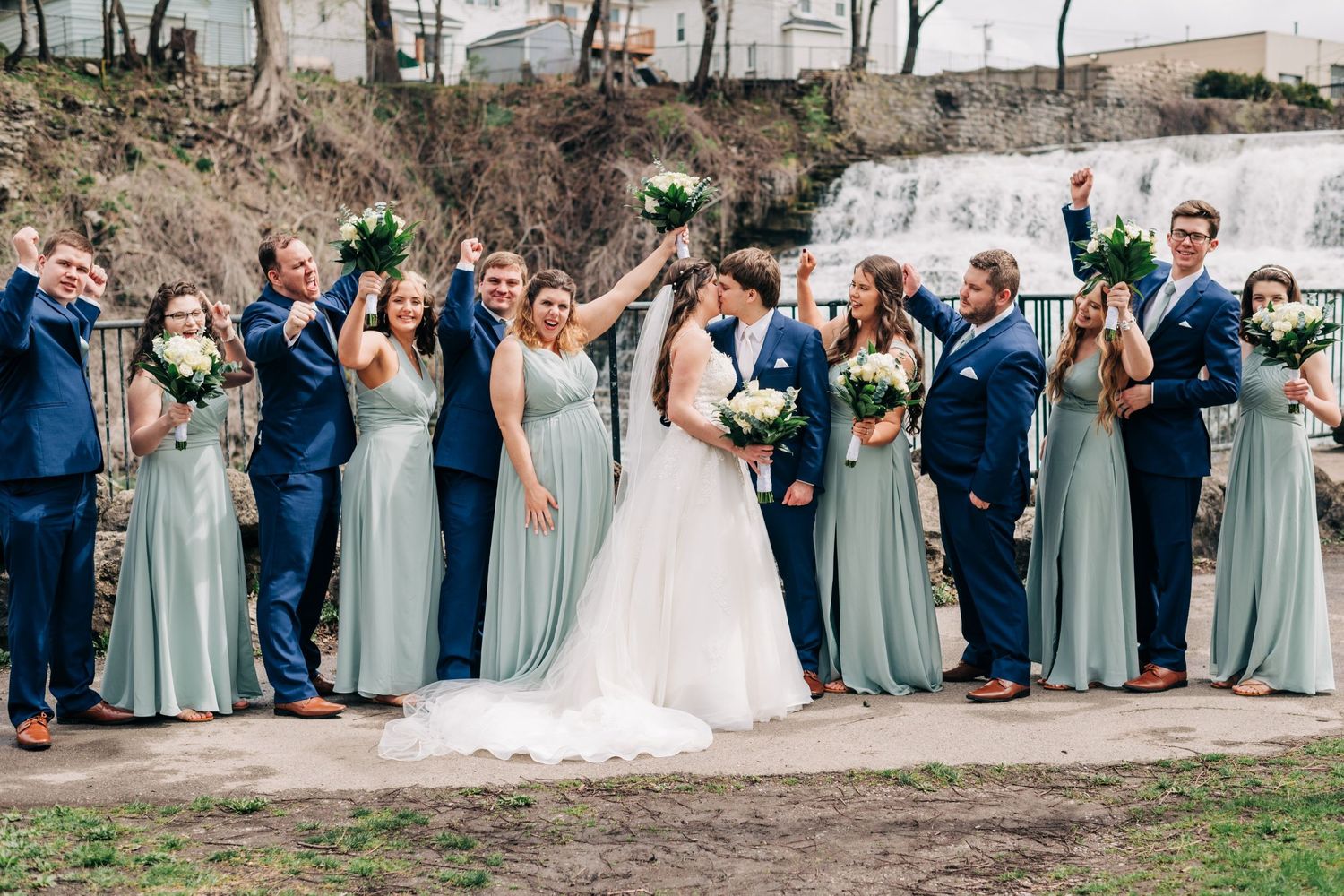 bridal party cheering for bride and groom in front of a waterfall