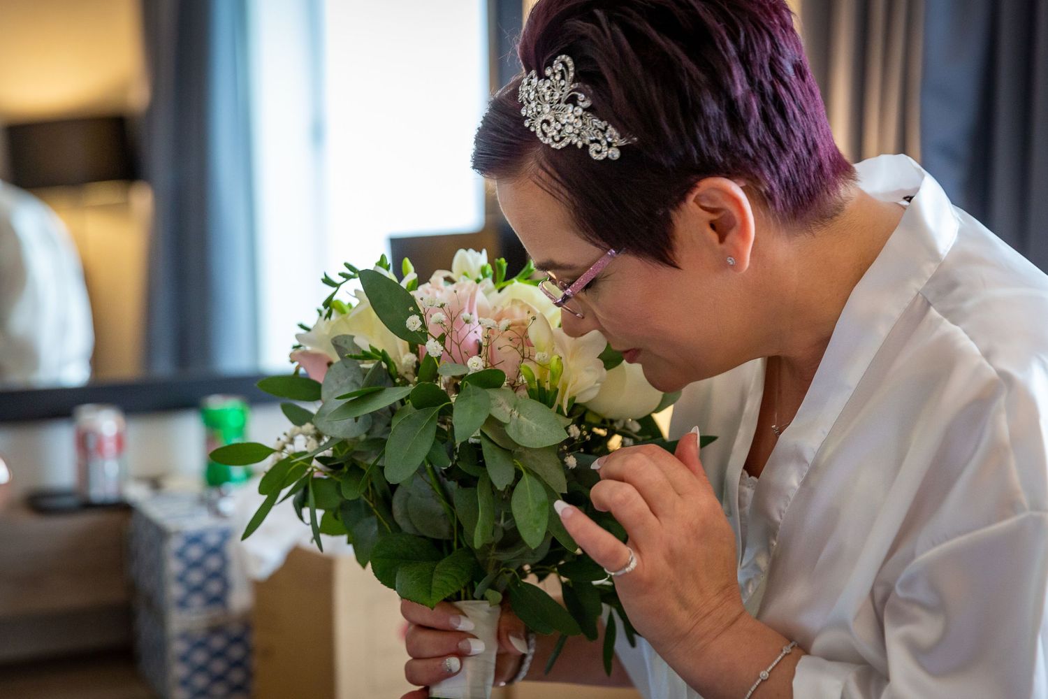 Bride in her dressing gown smells her bridal bouquet at the Crowne Plaza Hotel Liverpool. Liverpool wedding photography.