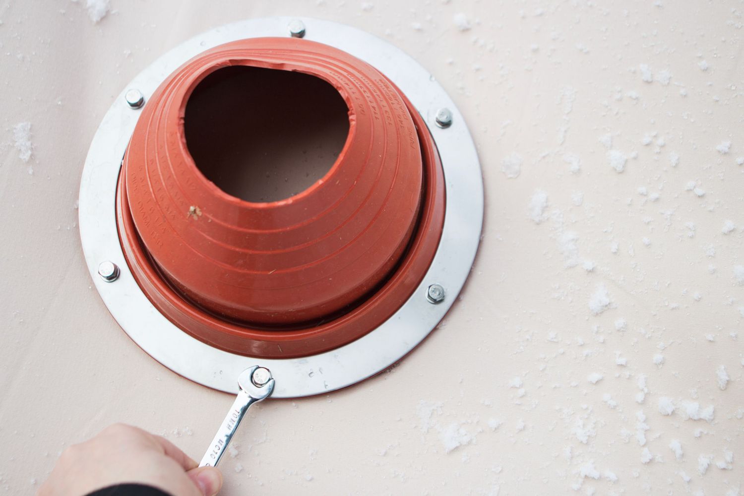 Red silicone gasket being installed around metal stove pipe flange.