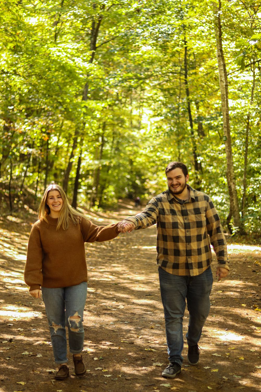 photo of a couple holding hands walking through the forest in New Hampshire adventure storytelling photographer
