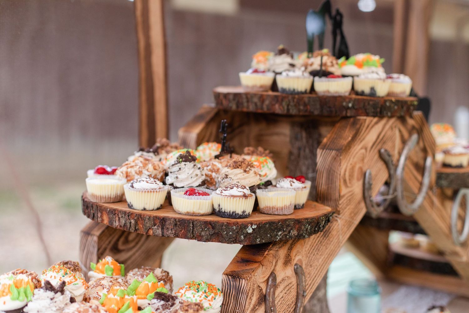 Multi-tiered wooden dessert display with variety of decorated cupcakes.