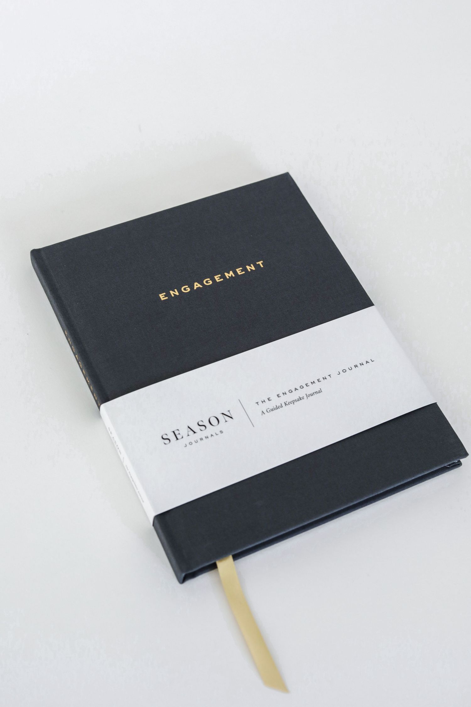 Dark grey hardcover engagement journal with gold lettering and white band detail.
