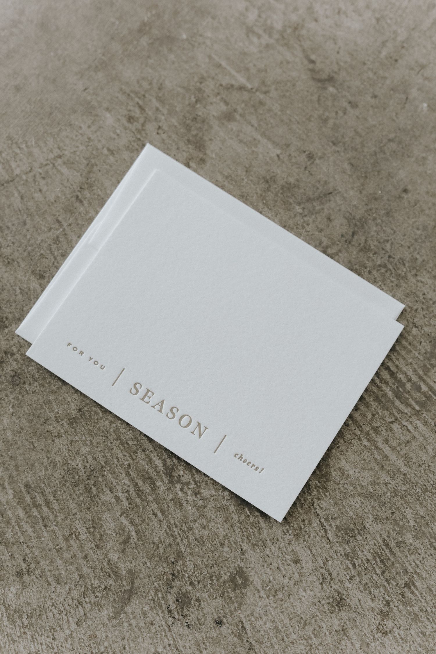 Minimalist white 'Season' journal or planner on concrete surface.