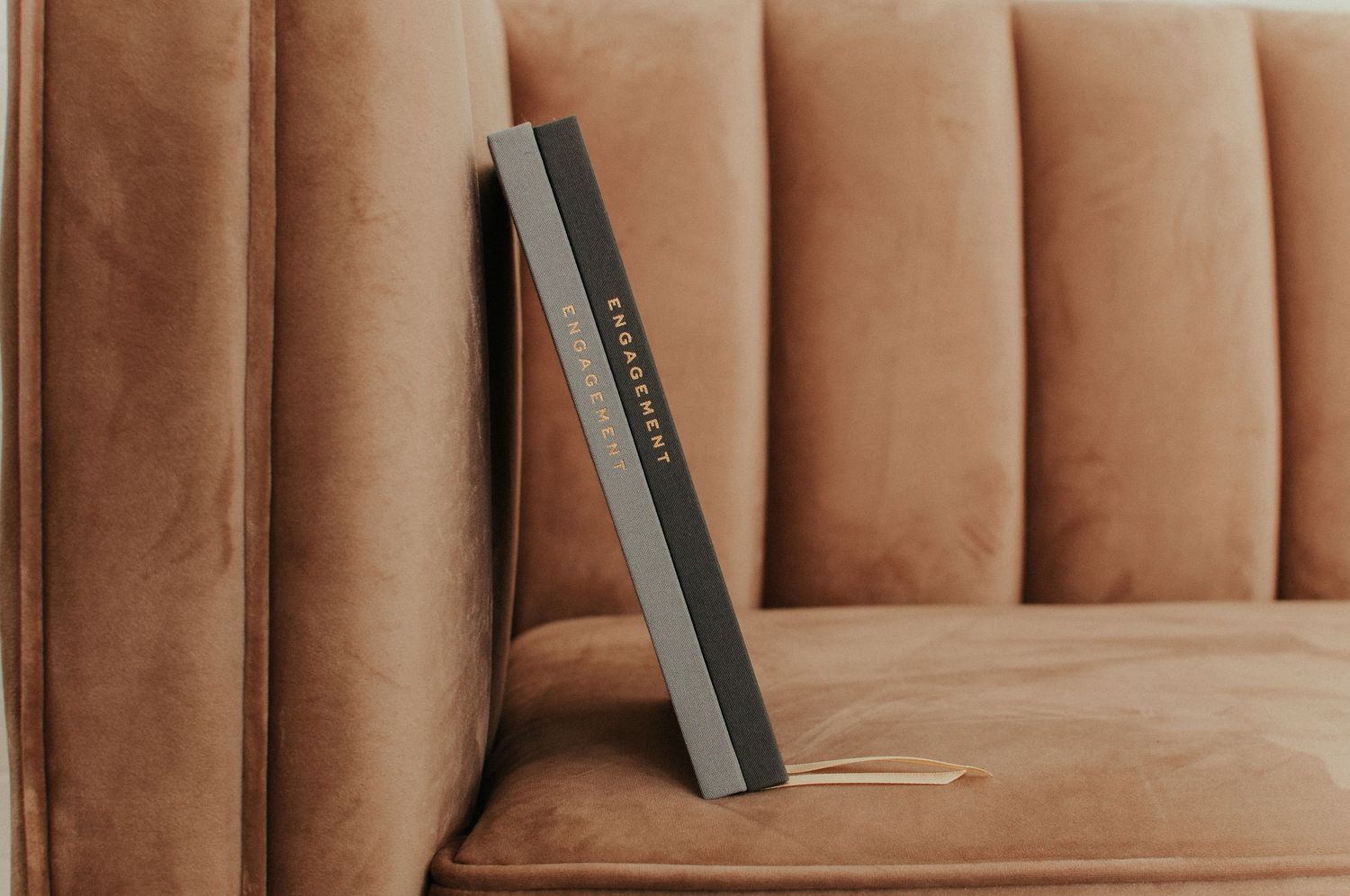 A leather book rests on a tan ribbed couch cushion.