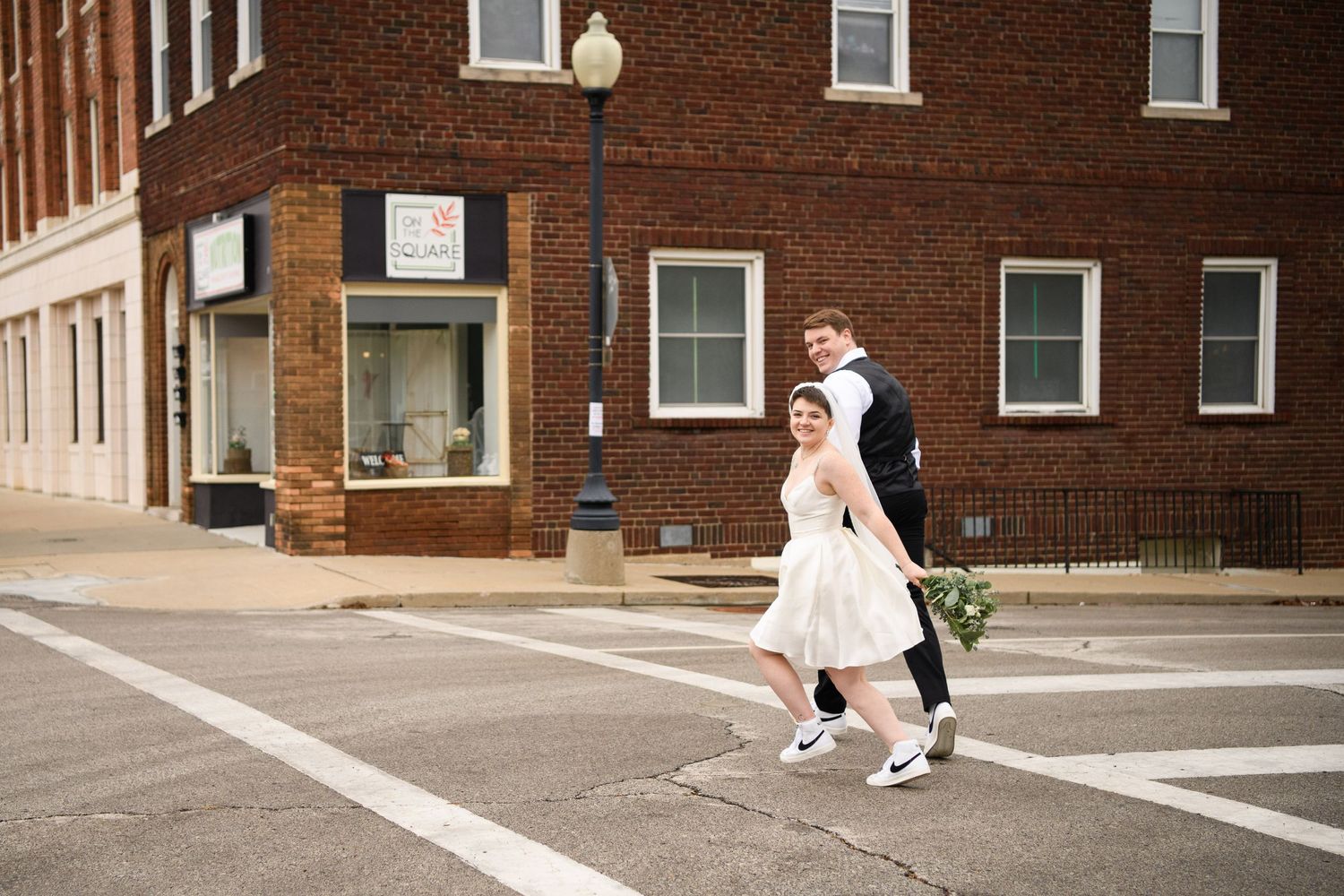A bride holding a bouquet while running with a groom in Liberty Missouri